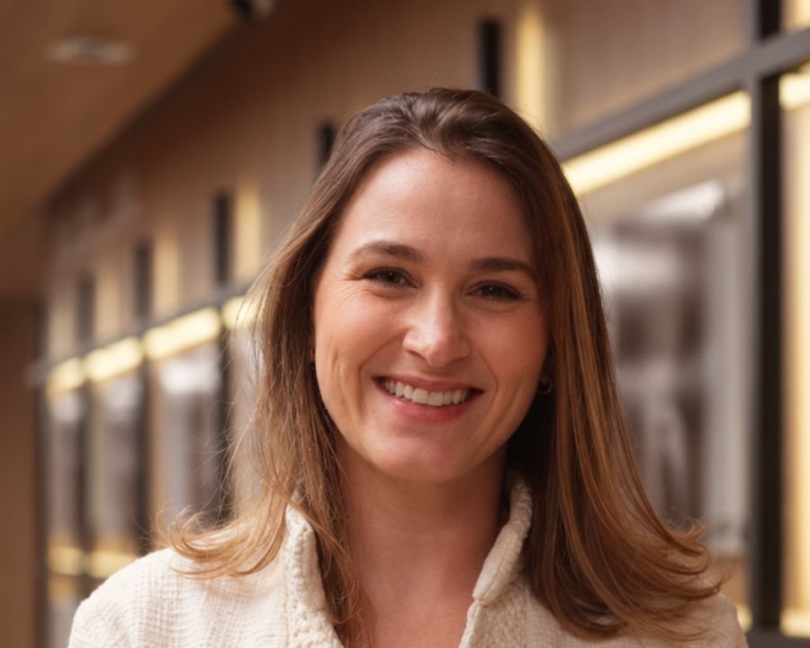 Dra. Fernanda Cano Casarotto sorrindo, de casaco claro, em um corredor do hospital
